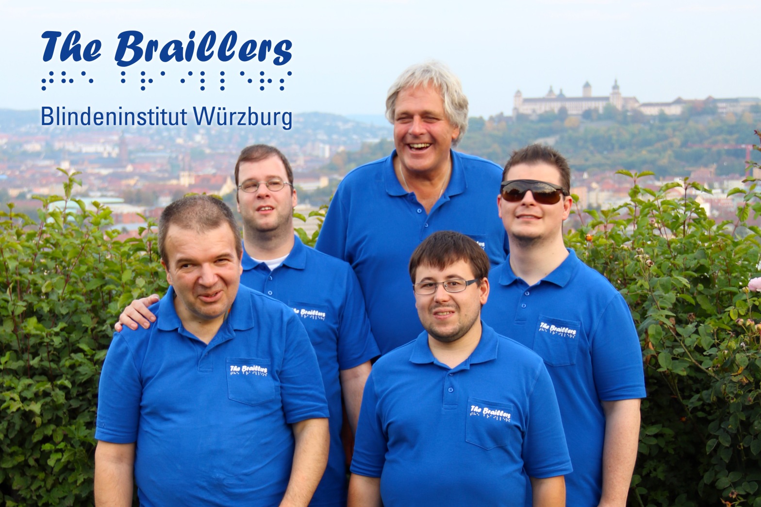 Foto von den fünf Mitgliedern der Band "The Braillers" in bleuen Band-T-Shirts, vor einer niedrigen Hecke, dahinter im Hintergrund das schöne Panorama von Würzburg, samt Burg, dazu das Logo der Band inklusive Schriftzug "Blindeninstitut Würzburg"